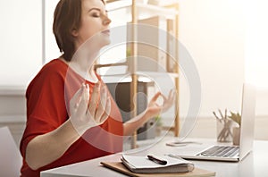 Business woman meditating near laptop