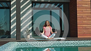 Business woman meditating near pool. Relaxed female making yoga exericise.