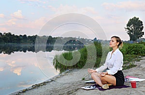 Business woman meditating on the shore