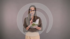 Business woman middleweight on an isolated yellow background makes notes in a ploknote. Woman in a business green shirt