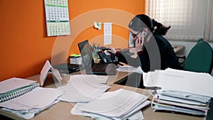 Business woman in office behind computer making a call