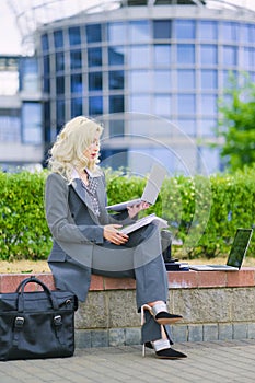 Business woman in an office suit working outside with a laptop computer. Vertical