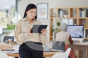 Business woman, office and working on digital tablet in the workplace with colleague in the background. Happy employee