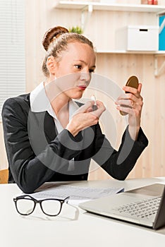 Business woman paints her lips with lipstick