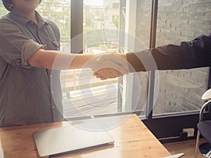 Business woman and partner shaking hands in office. vintage filter effect.