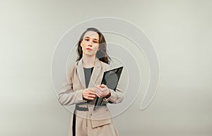 Business woman with pen and tablet stands with a pensive face on a yellow background, looking at the camera and thinking. 