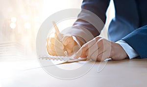 Business woman with pen writing on notebook in vibrant lighting