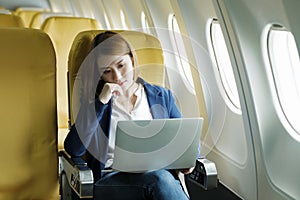 Business woman In a plane, works on using laptop computer.