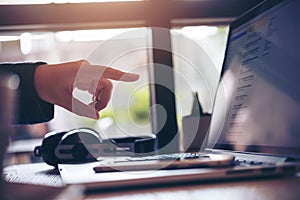 A business woman pointing her fingers at laptop in office with smart phone