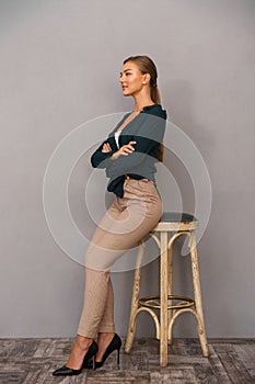 Business woman posing over grey wall background with arms crossed.