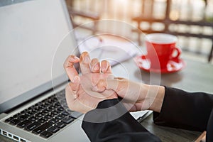 Business woman pressing the middle of her palm with her thumb to relieve pain due to a tendinitis caused by an excessive use of