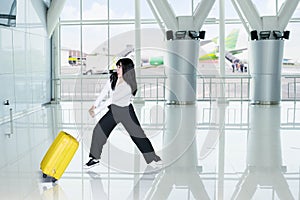 Business woman pulls her heavy luggage in airport