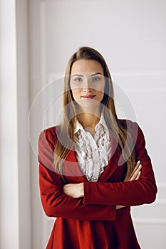 Business woman in red standing at modern office. Headshot of a young female entrepreneur photo