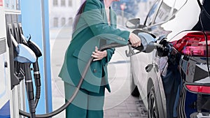 business woman refuels a car at a gas station.