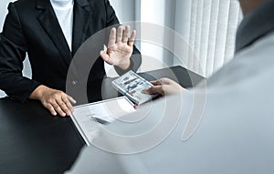 Business woman refusing and don`t receive money banknote in envelope offer from business people to accept agreement contract of