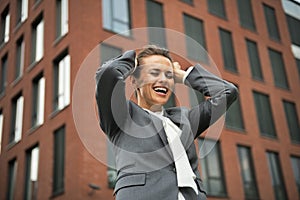 Business woman rejoicing in front of office