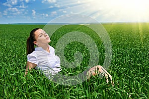 Business woman relaxing in green grass field outdoor under sun. Beautiful young girl dressed in suit resting, spring landscape, br