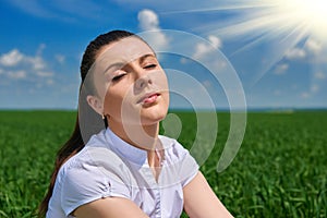 Business woman relaxing in green grass field outdoor under sun. Beautiful young girl dressed in suit resting, spring landscape, br