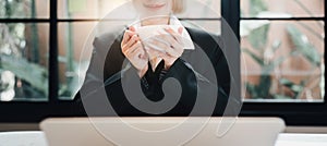 Business woman relaxing and holding hot drink and smiling at office