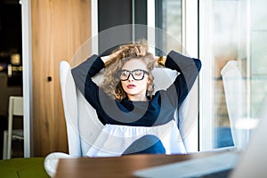 Business woman relaxing working at office desk laid back resting on chair with hands behind head.