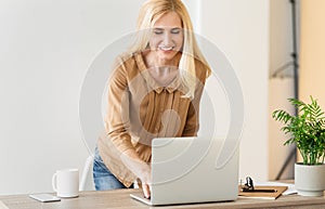 Business woman responding emails on laptop at workplace