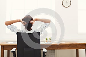 Business woman resting in office with hands behind her head