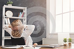 Business woman resting in office with hands behind her head