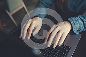 A business woman`s hands working and typing on laptop keyboard on the table