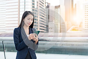 Business Woman sending sms on mobile phone in city
