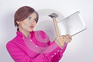 Business woman in a shirt smashes a tablet in her hands with a hammer