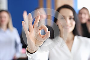 Business woman showing ok gesture on background of colleagues closeup