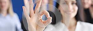 Business woman showing ok gesture on background of colleagues closeup