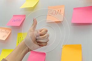 Business woman showing thumbs up with colored sheets sticky note paper on white board background