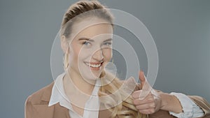 Business woman showing thumbs up on grey background. Happy businesswoman