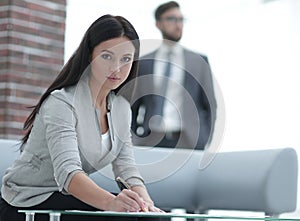 Business woman signs documents in a modern office.