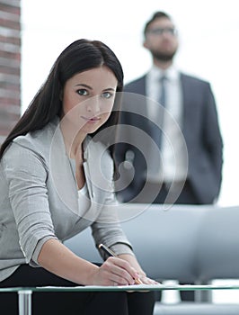 Business woman signs documents in a modern office.