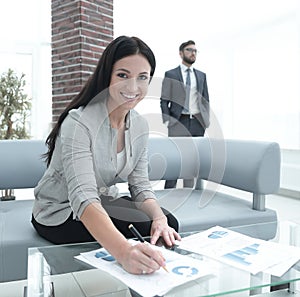 Business woman signs documents in a modern office.