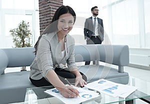 Business woman signs documents in a modern office.