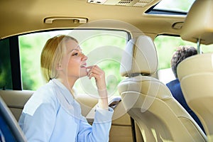 Business woman sit on backseat. Busy lady passenger leather car salon enjoy journey with chauffeur. Business lady