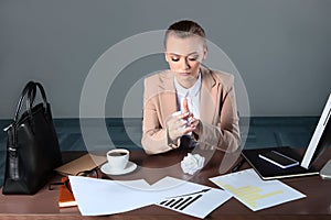 A business woman sits at a Desk and destroys documents. The woman crumples the sheets of paper. The concept of financial crisis.