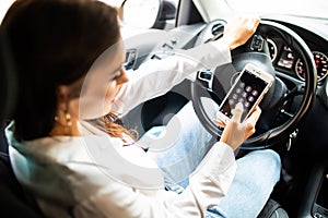 Business woman sitting in car and using her smartphone from back. Mockup image with female driver and phone screen