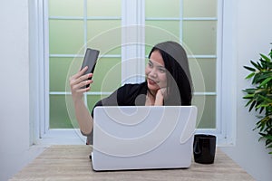 Business woman sitting on chair while making video call in front of laptop