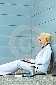 Business woman sitting on floor and using laptop
