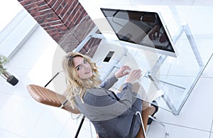 Business woman sitting at her Desk and looking at camera