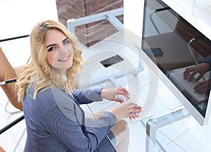 Business woman sitting at her Desk and looking at camera