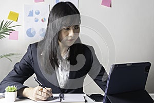 Business woman sitting in her office and checking the company`s earnings