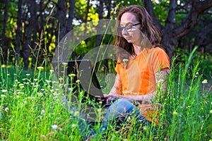 Business woman sitting with laptop in the park, free space.