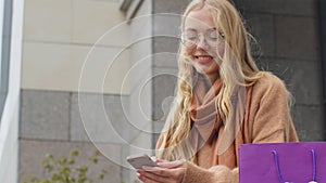 Business woman sitting near building outdoors close-up attractive young girl communicates using phone female shopper