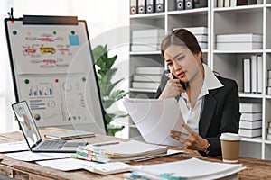 business woman sitting at office desk in front of laptop hold mobile phone make pleasant business or informal call