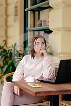 Business woman sitting at a table in a cafe and working thinking